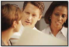 Three coworkers reviewing a project file.